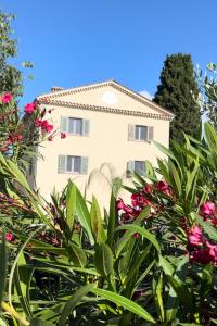 un bâtiment avec des fleurs roses devant lui dans l'établissement 3 pièces au dernier étage dans bastide grassoise, à Grasse