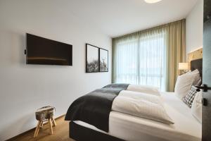 een slaapkamer met een groot bed en een tv aan de muur bij Stilvolle Luxuswohnung in der Residenz Silvretta in See