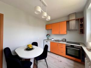 a kitchen with orange cabinets and a white table and chairs at Tytuvėnai-trumpalaikė nuoma in Tytuvėnai