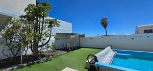 a backyard with a swimming pool and green grass at Direktly at our Swimming pool - Relax - Aduls only in Tías