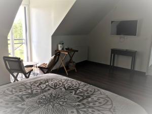 Fatouville-GrestainにあるAux portes d'Honfleurのベッドとテーブルとテレビのある寝室