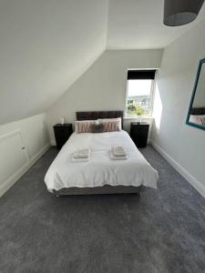 una camera da letto bianca con un letto con due asciugamani sopra di Bobbys Studio a Belmullet Altre 23 foto