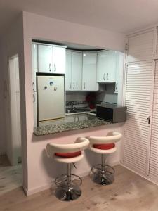 a kitchen with white cabinets and two bar stools at Carihuela Beach in Torremolinos
