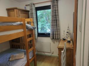 a bedroom with a bunk bed and a desk and a window at Bumbeldink in Uny Lelant