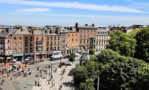 a city with people walking around a street with buildings at Clayton Hotel Burlington Road in Dublin