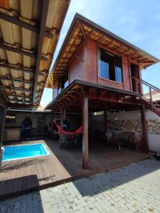 a house with a pool and a hammock on a deck at Edícula acolhedora in Serra