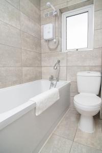 a bathroom with a tub and a toilet and a window at Quiet 3 bed house, pet friendly in Kirkby +16 photos