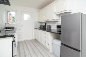 a white kitchen with white cabinets and a refrigerator at Quiet 3 bed house, pet friendly in Kirkby