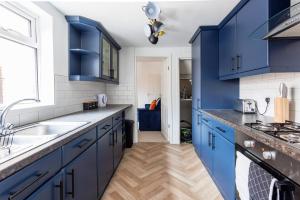 a kitchen with blue cabinets and a sink at Homey 4 Br Near The City Gateshead&newcastle in Dunston +25 photos