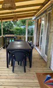 einen schwarzen Tisch und Stühle auf einer Veranda in der Unterkunft ESCALE BASSIN- Mobile Home Lège Cap-Ferret - Village 4 étoiles LES VIVIERS in Lège-Cap-Ferret