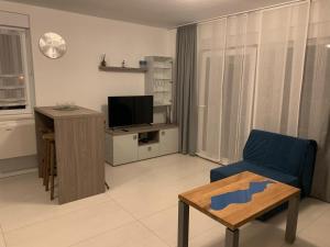 a living room with a blue chair and a television at Apartments Chico in Sveti Filip i Jakov