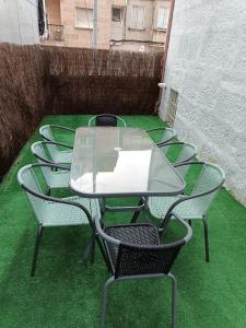 a glass table and chairs on a patio with green grass at Casa Miguel in Teis