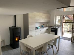 a kitchen with a white table and a fireplace at Rustico sui Monti di Rima in Broglio