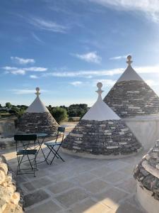 un patio avec deux chaises et deux structures en pierre dans l'établissement I PapaTrulli MiniResort, à Martina Franca