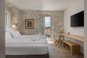 马卡尔斯卡Casa Columba - 4 Star Design Boutique Hotel with Outdoor Pool & Private Garden的一间卧室配有两张床和一张书桌及电视