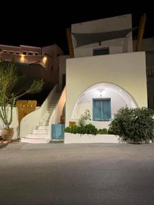 a white house with an arched window and stairs at Atlantida Spacious Flat in Fira