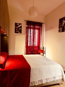 a bedroom with a bed and a window with red curtains at Sa domo de ziu Pedru in Sennori