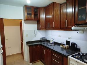 a kitchen with wooden cabinets and a black counter top at Camba Cua Relax in Corrientes