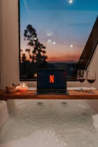 a laptop computer sitting on a bath tub with two wine glasses at Cabana Jurupará in Piedade