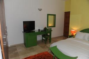 um quarto com uma cama e uma secretária com uma televisão em Residence Helios em Abidjan