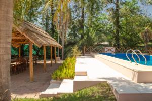 ein Resort mit einem Pool, einem Tisch und einem Strohschirm in der Unterkunft Casa de vacaciones con piscina y espacio recreativo in Santiago del Estero