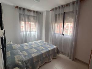 a bedroom with a bed and two windows at La caleta in Oropesa del Mar
