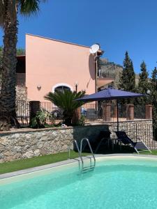 a swimming pool in front of a building with an umbrella at Villa Mimma in Taormina