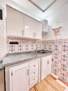 a kitchen with white cabinets and tiles on the wall at Dar Chemous -2- دار شموس in Tangier +7 photos