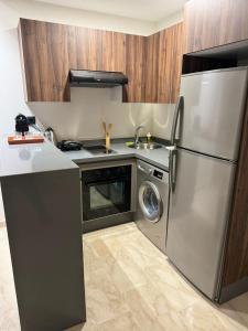 La cuisine est équipée d'un réfrigérateur en acier inoxydable et d'un lave-vaisselle. dans l'établissement Magic Living LUXURY 27 Neuf avec Smart TV, à Casablanca