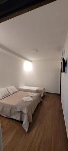 a room with two beds and a light on the wall at Chalé Campo Florido in São Roque de Minas