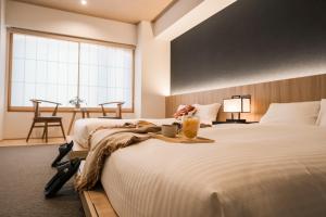 ein Hotelzimmer mit einem großen Bett und einem Getränk darauf in der Unterkunft WAYFARER Shin in Kyoto + 40 Fotos