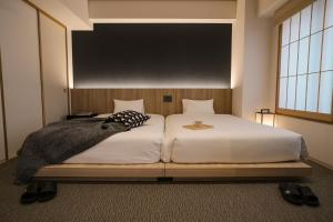 ein Schlafzimmer mit einem großen weißen Bett mit einem Brett an der Wand in der Unterkunft WAYFARER Shin in Kyoto