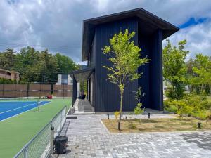 a tree in front of a building with a tennis court at Mount Fuji view BBQ プライベートテニスコート付き高級リゾートヴィラ MAAA in Fujikawaguchiko