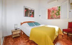 a bedroom with a bed with a yellow blanket and a window at 2 Bedroom Awesome Home In Albitreccia in Albitreccia