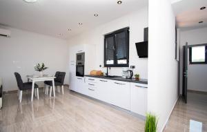 a kitchen with white cabinets and a table with chairs at Nice Apartment In Brodarica With Sauna in Brodarica