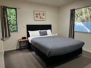 a bedroom with a bed and two windows at Bassingers Motor Lodge in Levin +18 photos