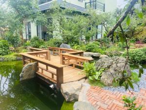 a wooden bridge over a pond in a garden at Châu homestay - Mộc Châu , Sơn La in Mộc Châu