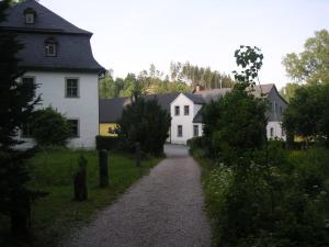 a gravel road in a village with white houses at Hammerschloss Unterklingensporn in Naila