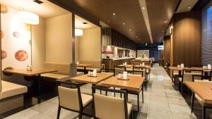 a dining room with wooden tables and chairs at Dormy Inn Kumamoto Natural Hot Spring in Kumamoto
