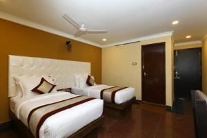 a hotel room with two beds in a room at Hotel Titanium Tower in Chennai +3 photos