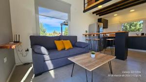 Una sala de estar con un sofá azul y una mesa. en Camino al Rio, en Dina Huapi