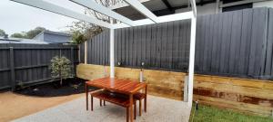 a wooden bench sitting next to a fence at Mysa Anglesea Sleeps 7 WiFi SmartTV Cafes Shops in Anglesea