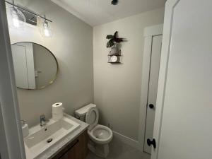 een badkamer met een wastafel, een toilet en een spiegel bij Platinum Homes Stylish 3BR Home Near Moncton, Dieppe Airport Free Parking in Dieppe +15 foto's