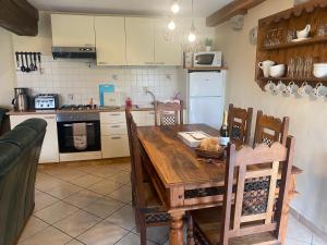 a kitchen with a wooden table and chairs and a kitchen with white appliances at The Gingerbread House Cottage in Beauficel
