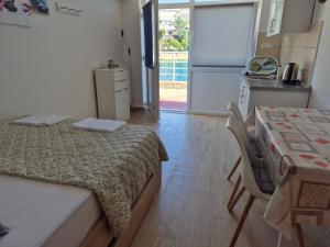 a bedroom with a bed and a table and a kitchen at Apartmani Niko in Neum