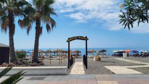 a sign on a beach with palm trees and umbrellas at Panorama Beach - Sea Breeze Apartment in Torrox Costa