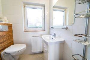a white bathroom with a toilet and a sink at Apartamenty i pokoje Seeblick in Mikołajki +44 photos