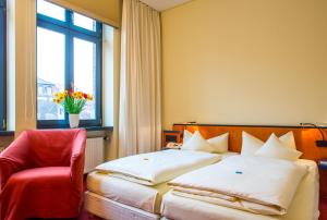 a bedroom with a bed and a red chair and a window at Hotel zum Ritter in Fulda