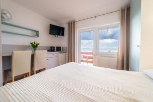 a bedroom with a bed and a kitchen with a window at Apartamenty i pokoje Seeblick in Mikołajki