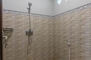 a shower in a bathroom with a tile wall at Pusaka Rinjani Bungalow in Sembalun Lawang